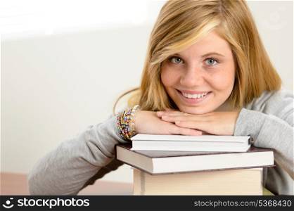 Smiling student teenager leaning head on stack of books