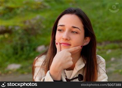 Smiling teen girl thinking outside with a natural green of background