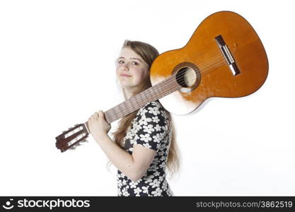 smiling teenage girl in dress holds guitar on shoulder in studio with white background