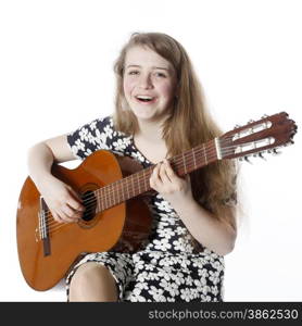 smiling teenage girl in dress plays the guitar in studio with white background
