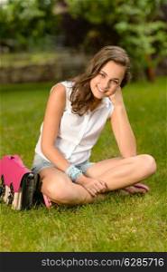 Smiling teenage girl sitting on grass with pink satchel summer