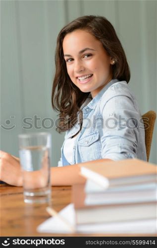 Smiling teenage girl student at home books side view