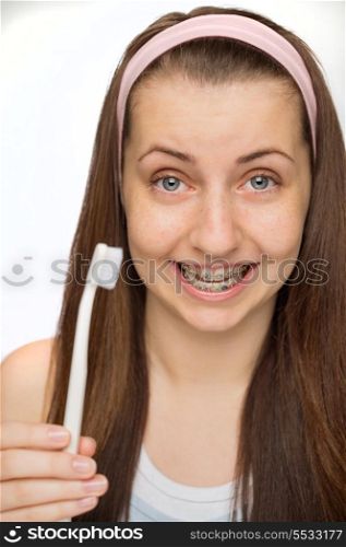 Smiling teenage girl wearing braces showing toothbrush on white background