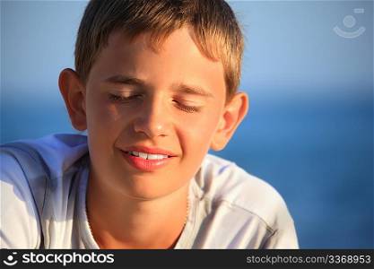 smiling teenager boy against sea, closed eyes