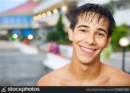 smiling teenager boy standing near hotel on resort in evening