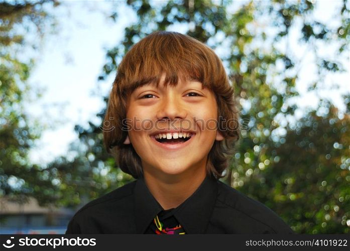 Smiling teenager dressed up in a black shirt and tie.