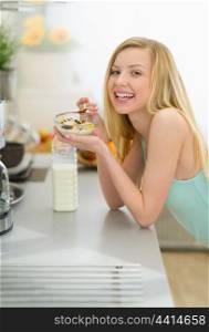Smiling teenager girl eating breakfast in kitchen