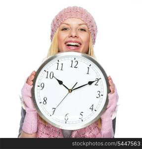Smiling teenager girl in winter hat and scarf hiding looking out from clock