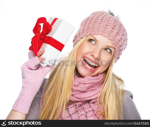 Smiling teenager girl in winter hat and scarf shaking presenting box