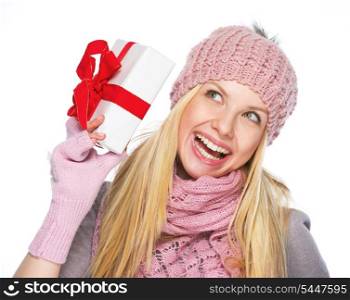 Smiling teenager girl in winter hat and scarf shaking presenting box