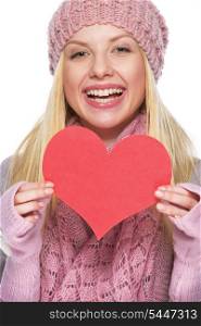 Smiling teenager girl in winter hat and scarf showing heart shaped postcard