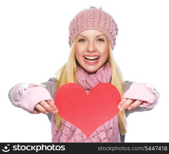 Smiling teenager girl in winter hat and scarf showing heart shaped postcard