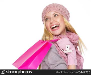 Smiling teenager girl in winter hat and scarf with shopping bag looking on copy space