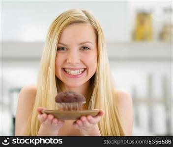 Smiling teenager girl showing chocolate muffin