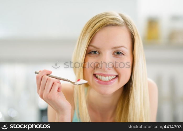Smiling teenager girl with spoon of yogurt