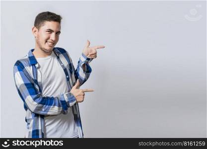 Smiling teenager pointing fingers to the side. smiling handsome man recommending something with his fingers. Caucasian handsome guy pointing his finger at a blank space