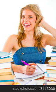 Smiling teengirl sitting at table with lots of books&#xA;