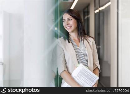 Smiling thoughtful businesswoman with documents at office