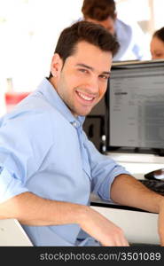 Smiling trader in front of desktop computer