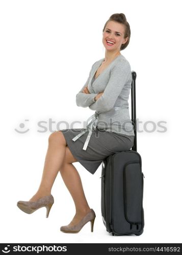 Smiling traveling woman sitting on suitcase