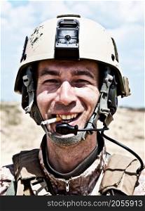 smiling US soldier in the desert smoking a cigarette