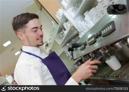 smiling waiter making cup of coffee at the coffee shop