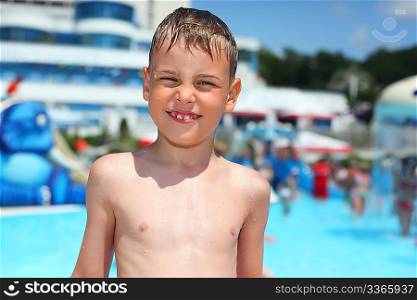 smiling wet boy near pool in aquapark of an entertaining complex