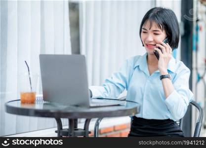 Smiling with dental braces asian freelance people business female hold pick up smartphone casual working with laptop computer with coffee cup and smartphone in coffee shop like the background