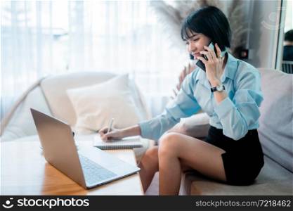 Smiling with dental braces asian freelance people business female hold pick up smartphone casual working with laptop computer and written Notes to on notebook with coffee cup in coffee shop