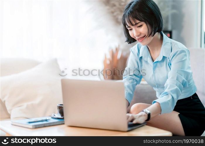 Smiling with dental braces of asian freelance people business female casual working with laptop computer and notebook with coffee cup and smartphone in cafe interior in coffee shop