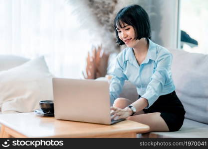 Smiling with dental braces of asian freelance people business female casual working with laptop computer and notebook with coffee cup and smartphone in cafe interior in coffee shop