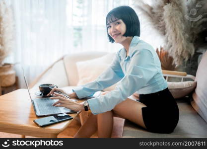 Smiling with dental braces of asian freelance people business female casual working with laptop computer and notebook with coffee cup and smartphone in cafe interior in coffee shop