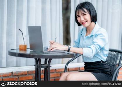 Smiling with dental braces of asian freelance people business female hold pick up smartphone written Notes to on notebook working with laptop computer with coffee cup and smartphone in coffee shop