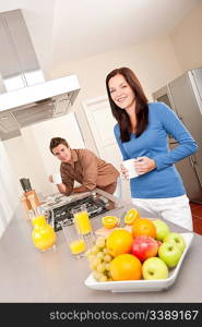 Smiling woman and man in the kitchen, having coffee and orange juice