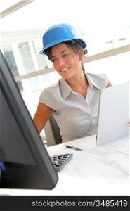 Smiling woman architect in office working on desktop computer