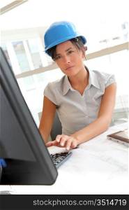 Smiling woman architect in office working on desktop computer