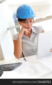Smiling woman architect in office working with electronic tablet