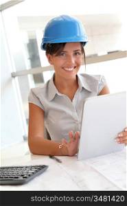 Smiling woman architect in office working with electronic tablet