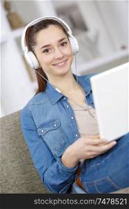 smiling woman at home relaxing with laptop and headphones