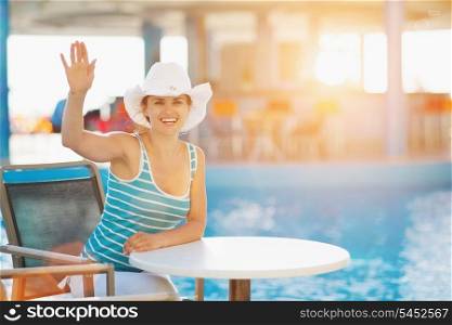 Smiling woman at pool bar saluting