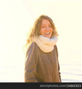 smiling woman at sea coast in winter, yellow toned