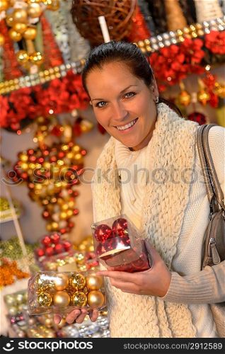 Smiling woman buying Christmas balls at shop