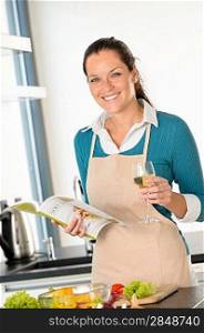 Smiling woman cooking home kitchen recipe book vegetables food wine