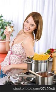 Smiling woman cooking spaghetti and tomato sauce, with white wine