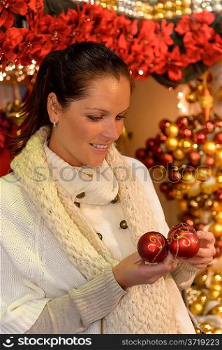 Smiling woman customer holding Christmas baubles at shop