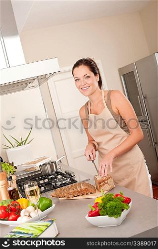 Smiling woman cutting bread in the kitchen