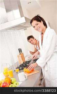 Smiling woman cutting oranges for breakfast in the kitchen