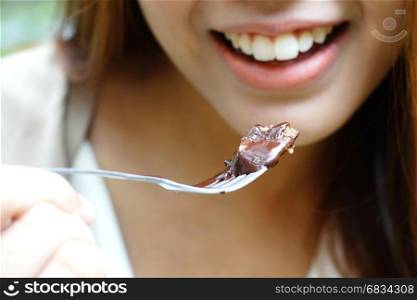 smiling woman eating chocolate cake with fork