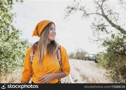 Smiling woman exploring old railroad tracks with her backpack and enjoying the surroundings