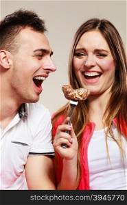 Smiling woman feeding happy man with cake.. Smiling woman feeding happy man with cake. Wife and husband eating caloric food.